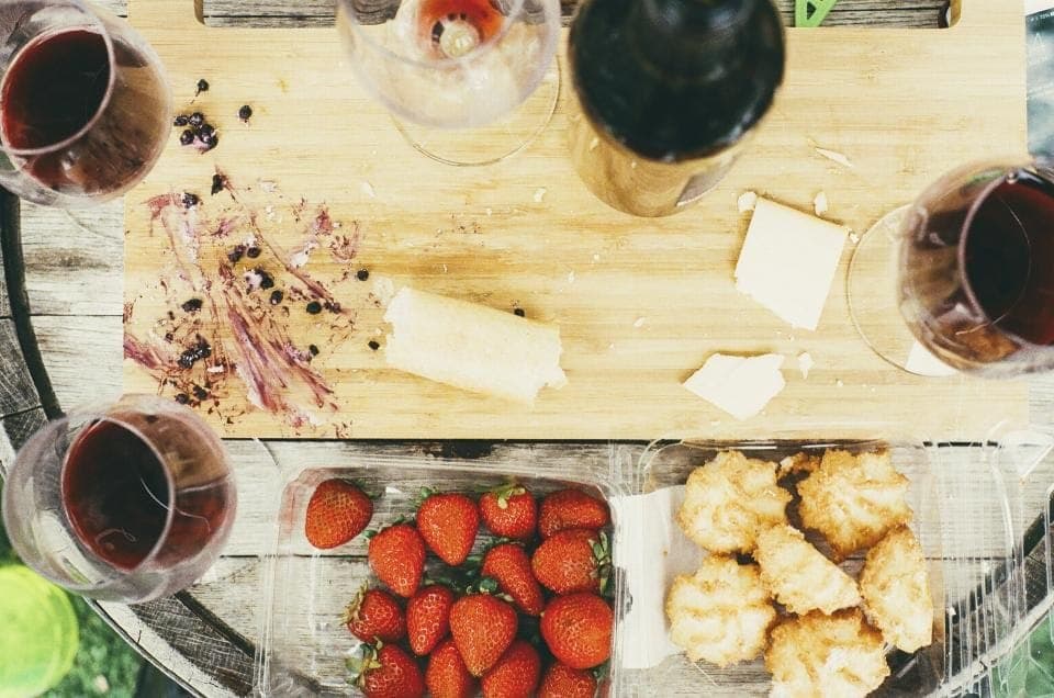 Verres de vin rouge et planche de fromages sur une table en bois, vue du dessus